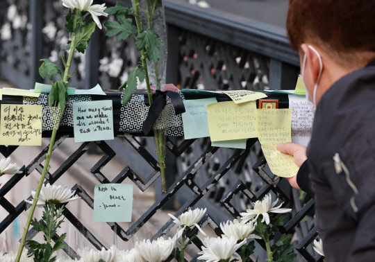 1일 서울 용산구 이태원역 1번 출구 앞 참사 추모 공간에서 한 시민이 추모의 메시지를 부착하고 있다. 연합뉴스